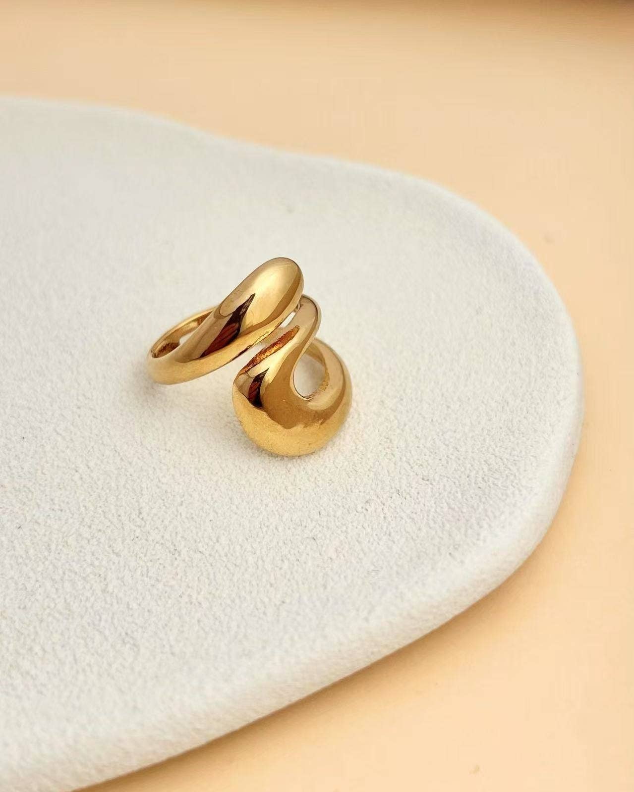 Mirael Ring adjustable gold-tone stainless steel ring with abstract sculptural design, photographed in soft neutral tones for the refined Atelier Épure aesthetic.