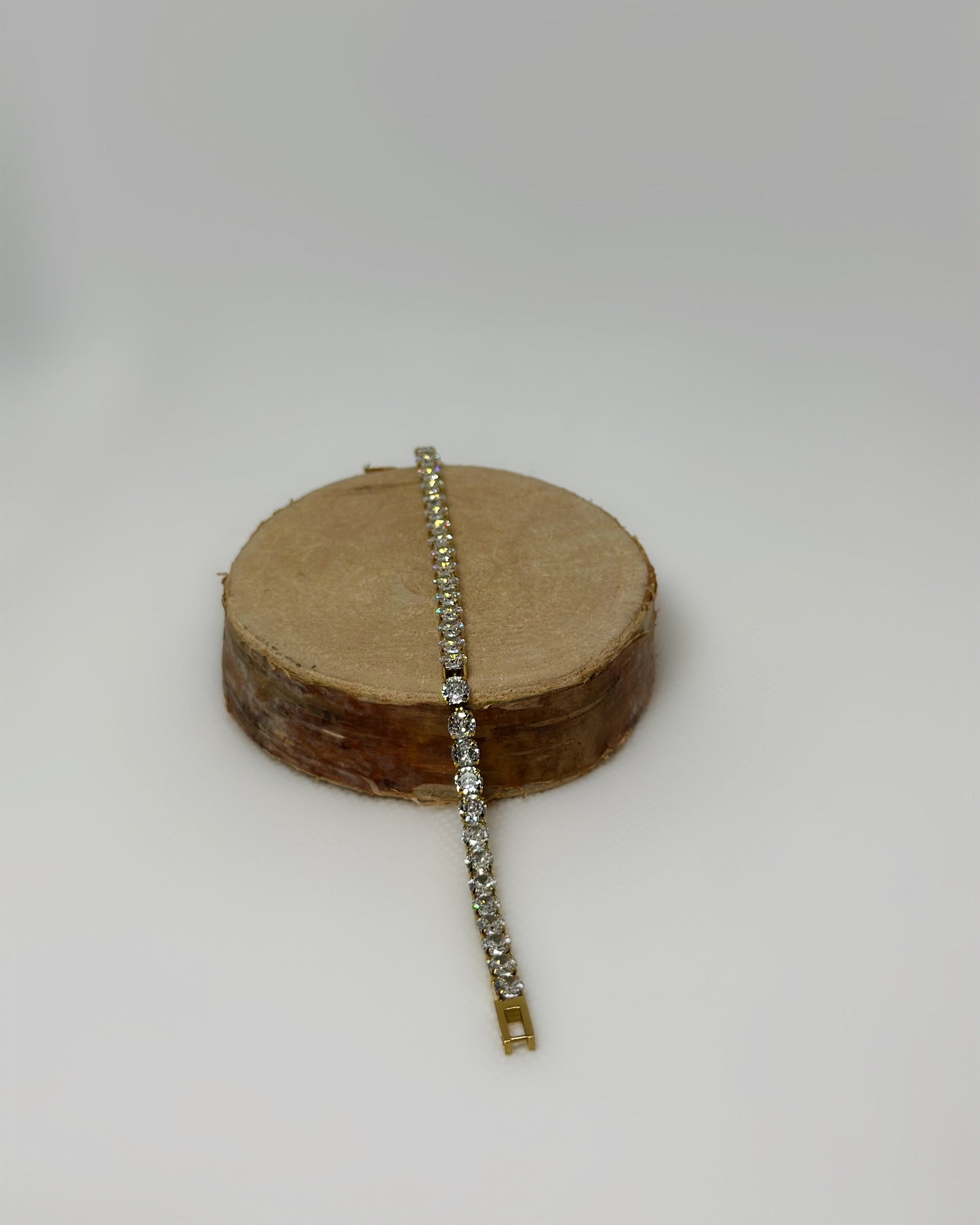 Lucente Bracelet, a gold stainless-steel tennis bracelet adorned with cubic zirconia stones, photographed on a soft neutral background, glowing under gentle light.