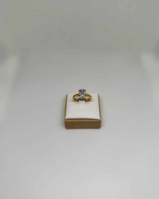 Close-up of the Vow Ring an 18K gold-plated stainless-steel statement ring featuring a pear-cut cubic zirconia, photographed on a soft neutral display.