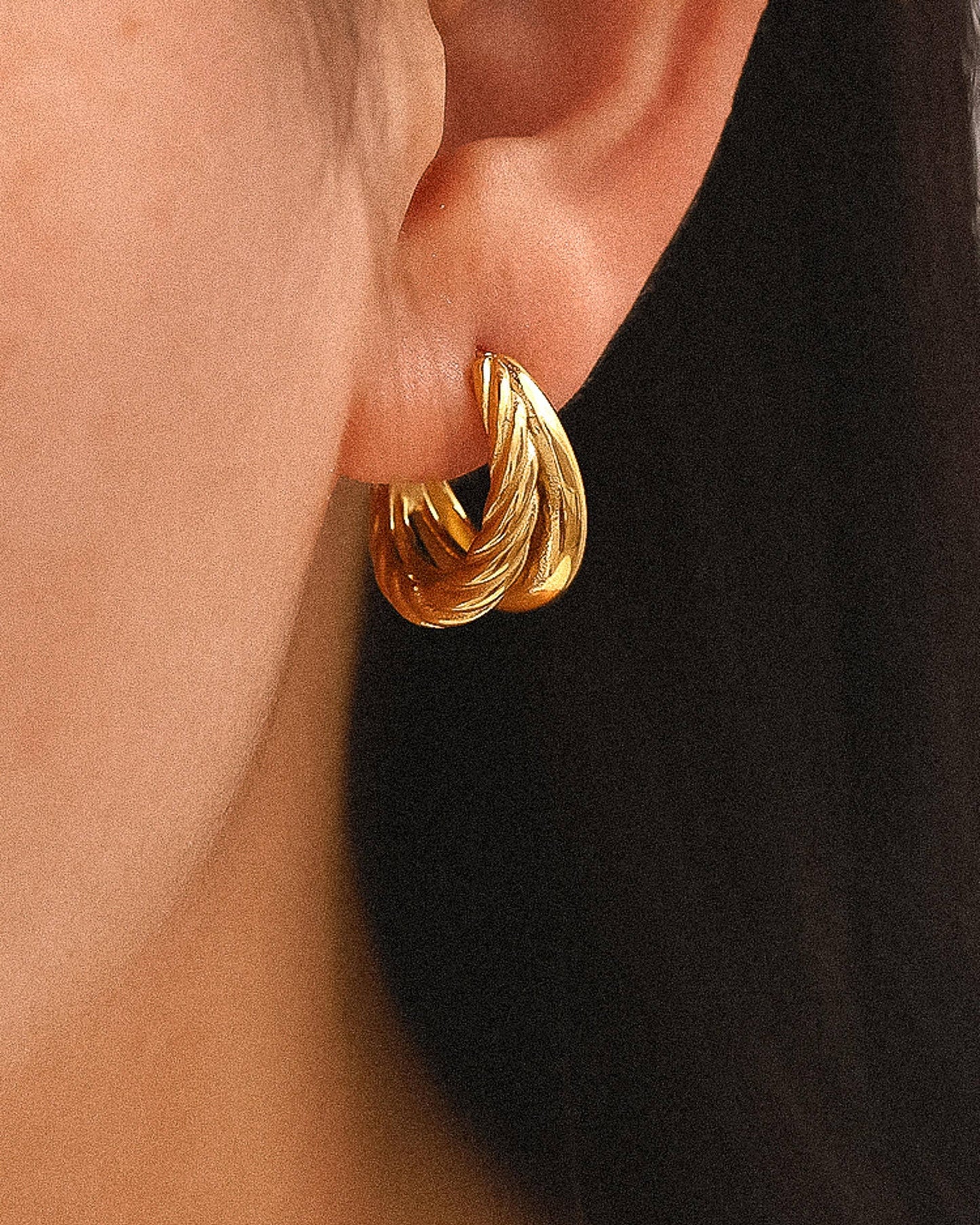 Aurum Twist Earrings, gold double-hoop earrings with braided and smooth textures, photographed on a neutral background with soft light for a refined luxury look.