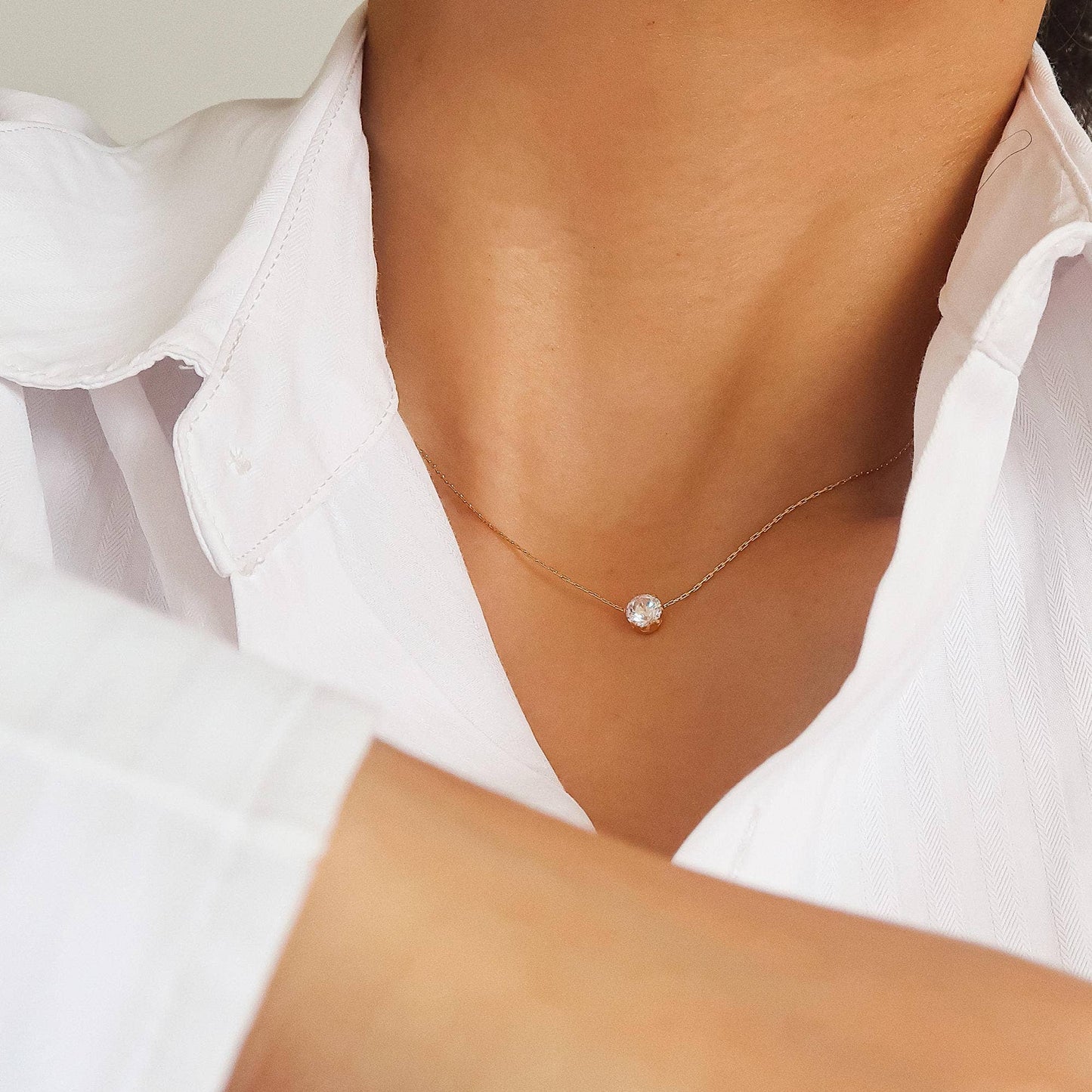 Close-up of the Serein Necklace, a dainty 18K gold-plated chain featuring a small round cubic zirconia pendant, photographed on a soft neutral display.