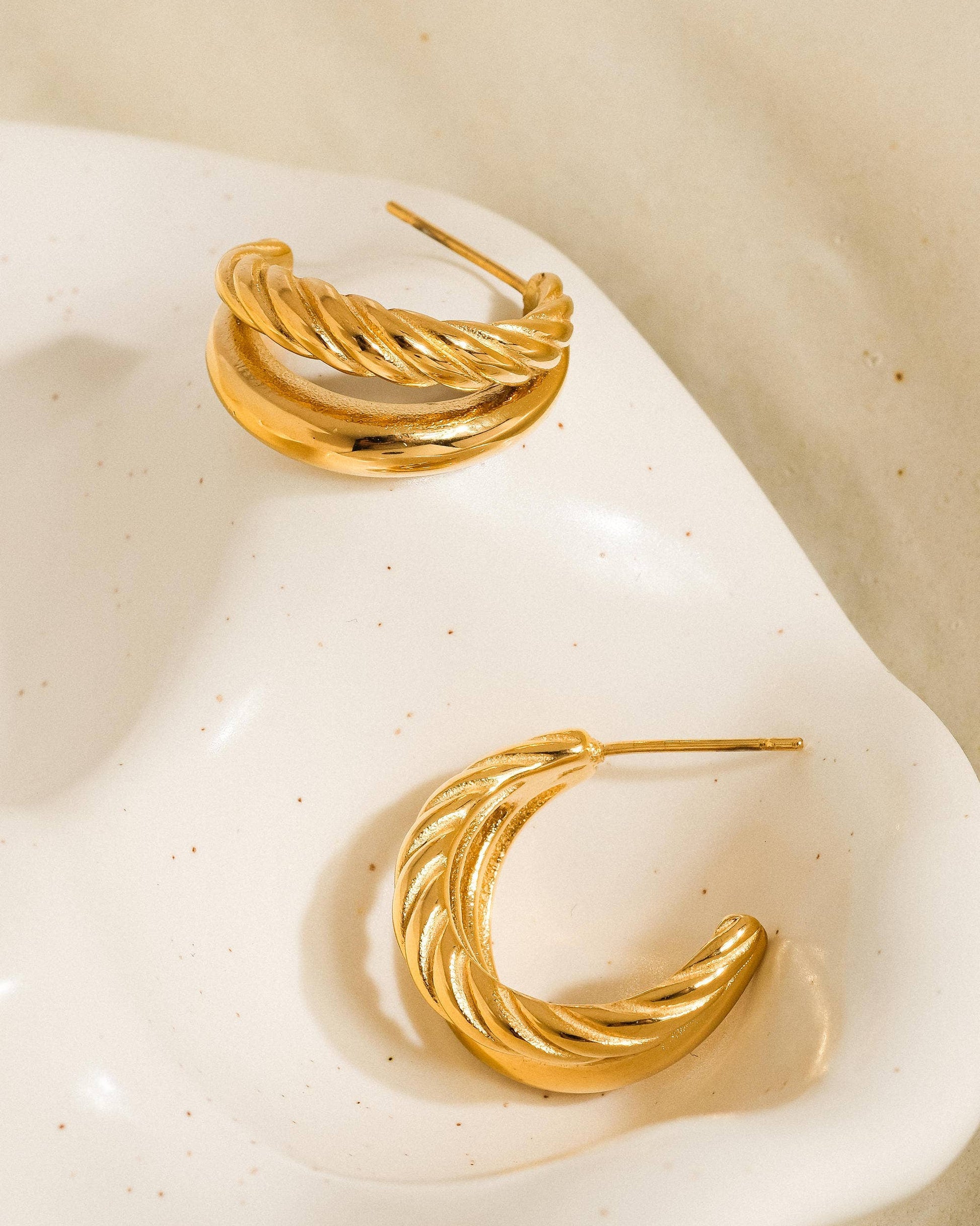 Aurum Twist Earrings, gold double-hoop earrings with braided and smooth textures, photographed on a neutral background with soft light for a refined luxury look.