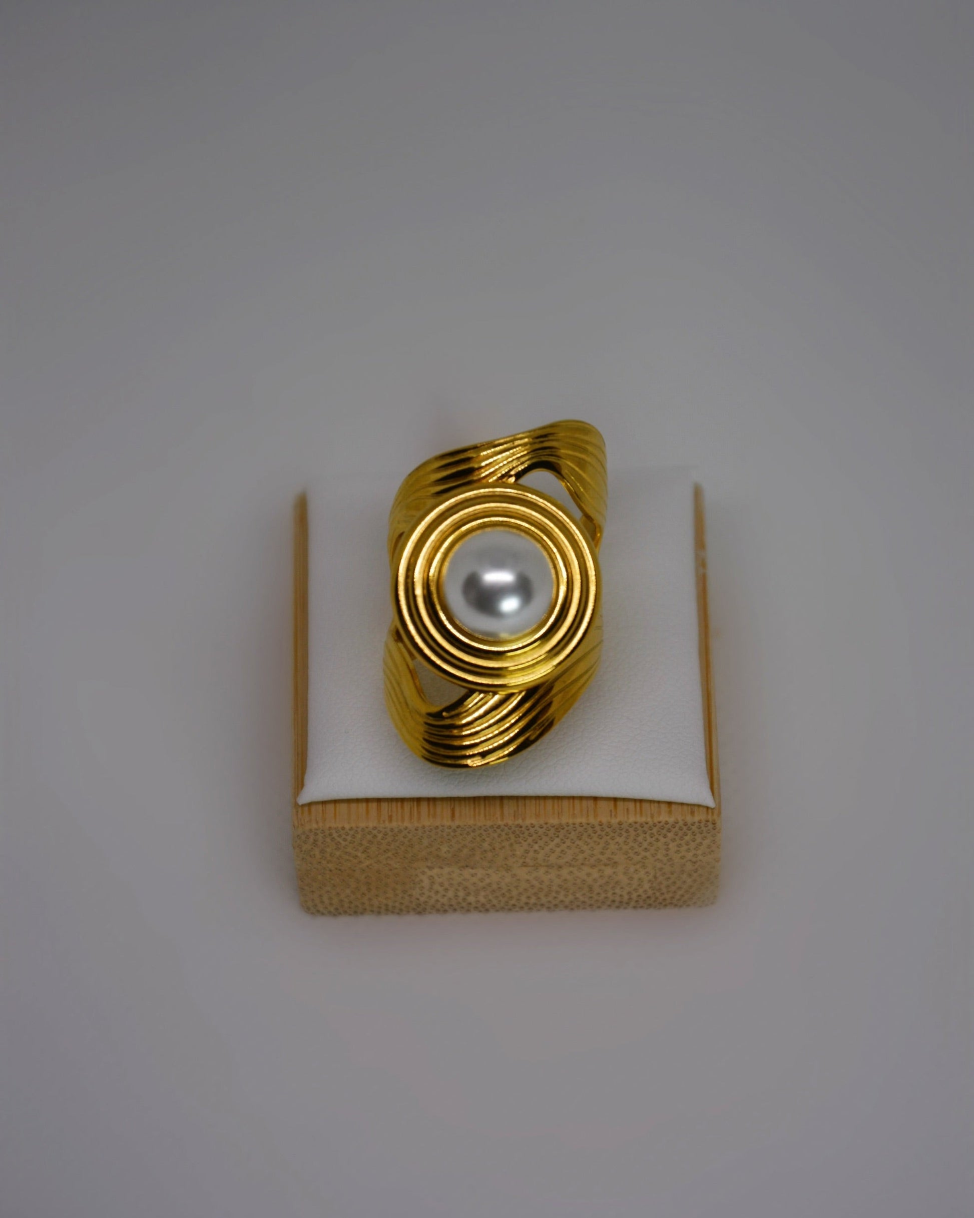 Cendréa Ring adjustable gold-tone stainless steel ring with wave texture and central pearl, photographed in soft neutral tones for a refined Atelier ÉPURE aesthetic.