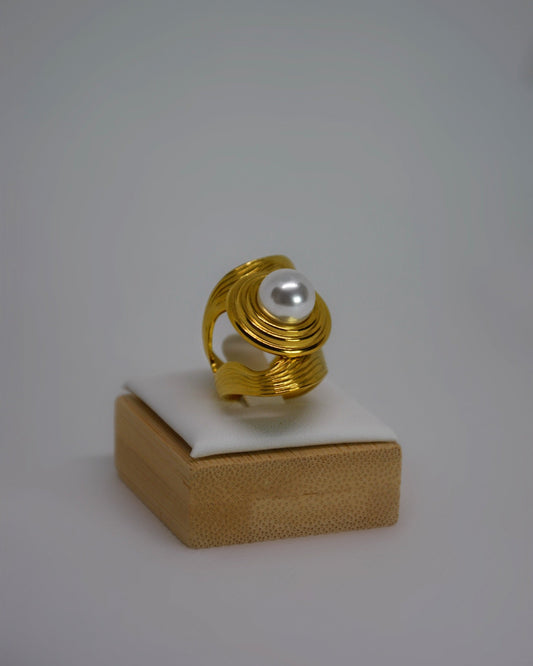 Cendréa Ring adjustable gold-tone stainless steel ring with wave texture and central pearl, photographed in soft neutral tones for a refined Atelier ÉPURE aesthetic.