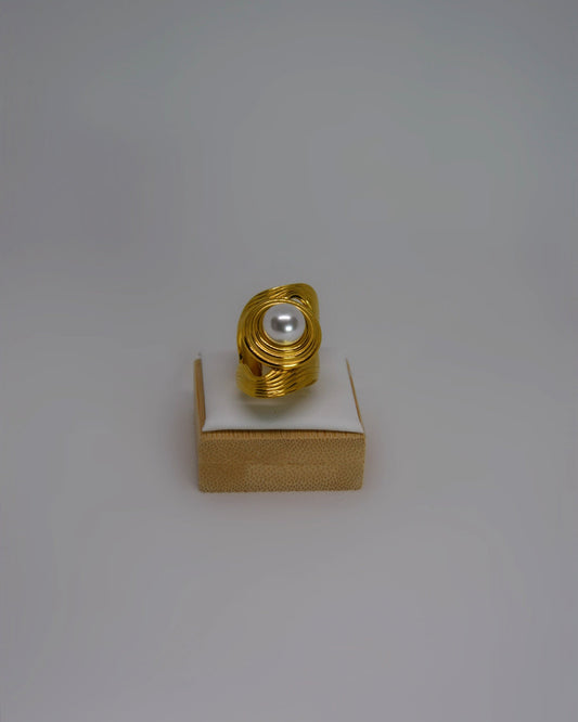 Cendréa Ring adjustable gold-tone stainless steel ring with wave texture and central pearl, photographed in soft neutral tones for a refined Atelier ÉPURE aesthetic.