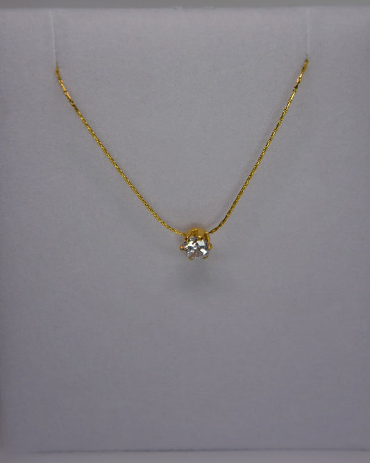 Close-up of the Serein Necklace, a dainty 18K gold-plated chain featuring a small round cubic zirconia pendant, photographed on a soft neutral display.