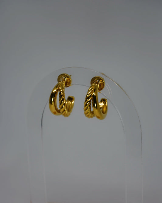 Aurum Twist Earrings, gold double-hoop earrings with braided and smooth textures, photographed on a neutral background with soft light for a refined luxury look.