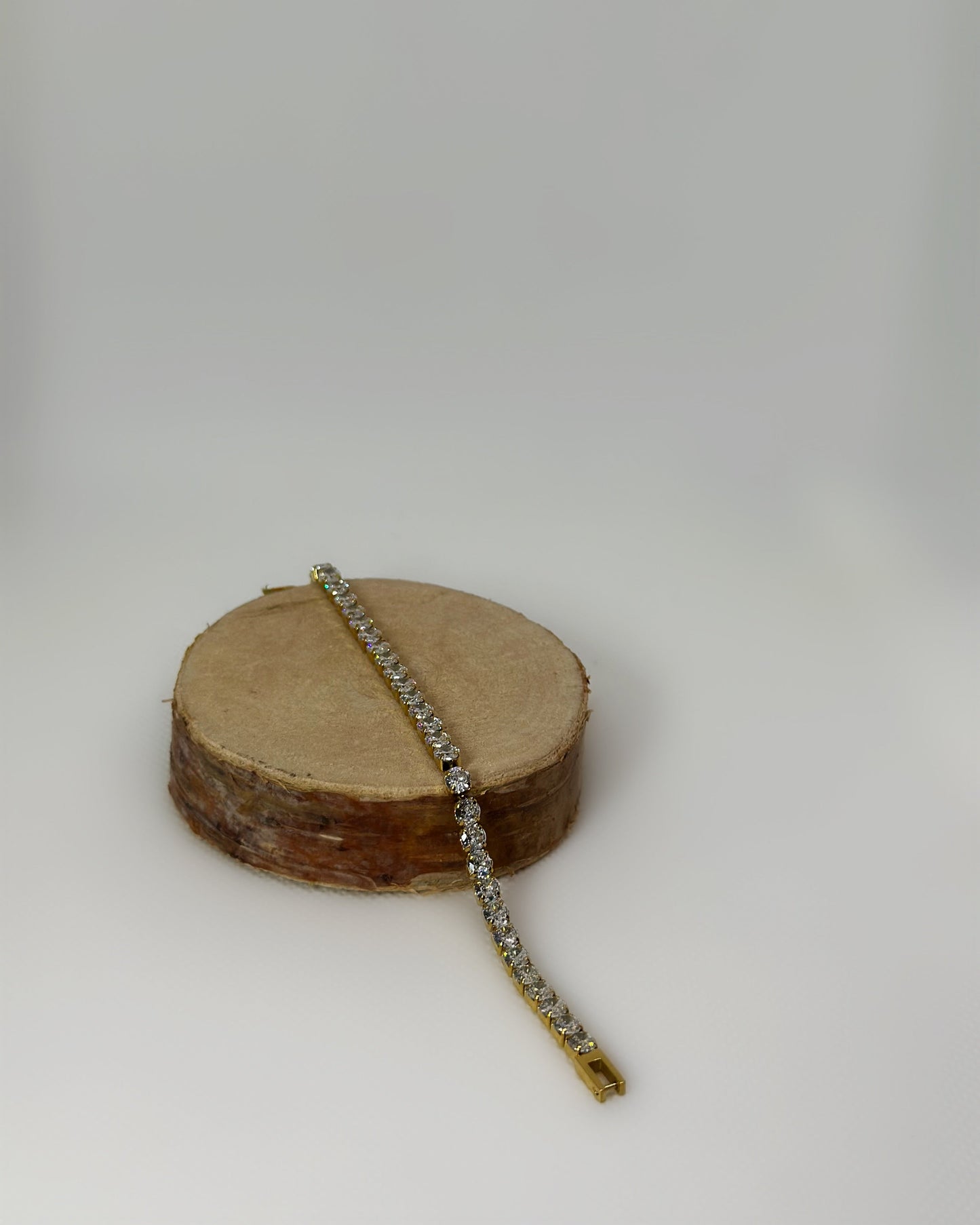 Lucente Bracelet, a gold stainless-steel tennis bracelet adorned with cubic zirconia stones, photographed on a soft neutral background, glowing under gentle light.