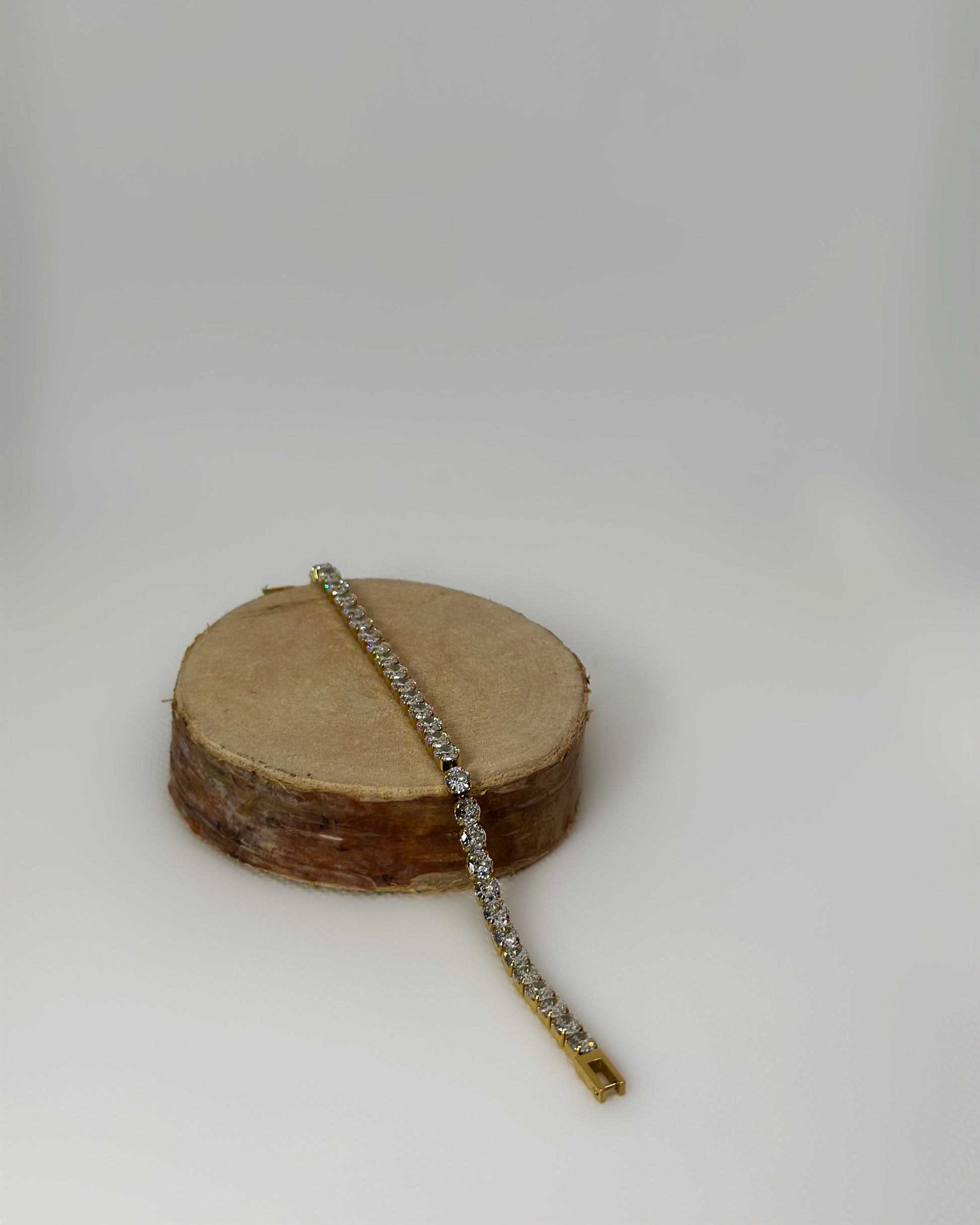 Lucente Bracelet, a gold stainless-steel tennis bracelet adorned with cubic zirconia stones, photographed on a soft neutral background, glowing under gentle light.