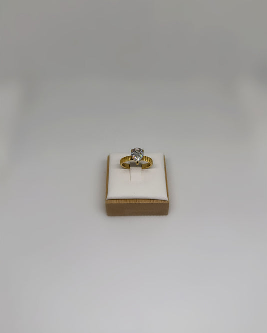 Close-up of the Vow Ring an 18K gold-plated stainless-steel statement ring featuring a pear-cut cubic zirconia, photographed on a soft neutral display.