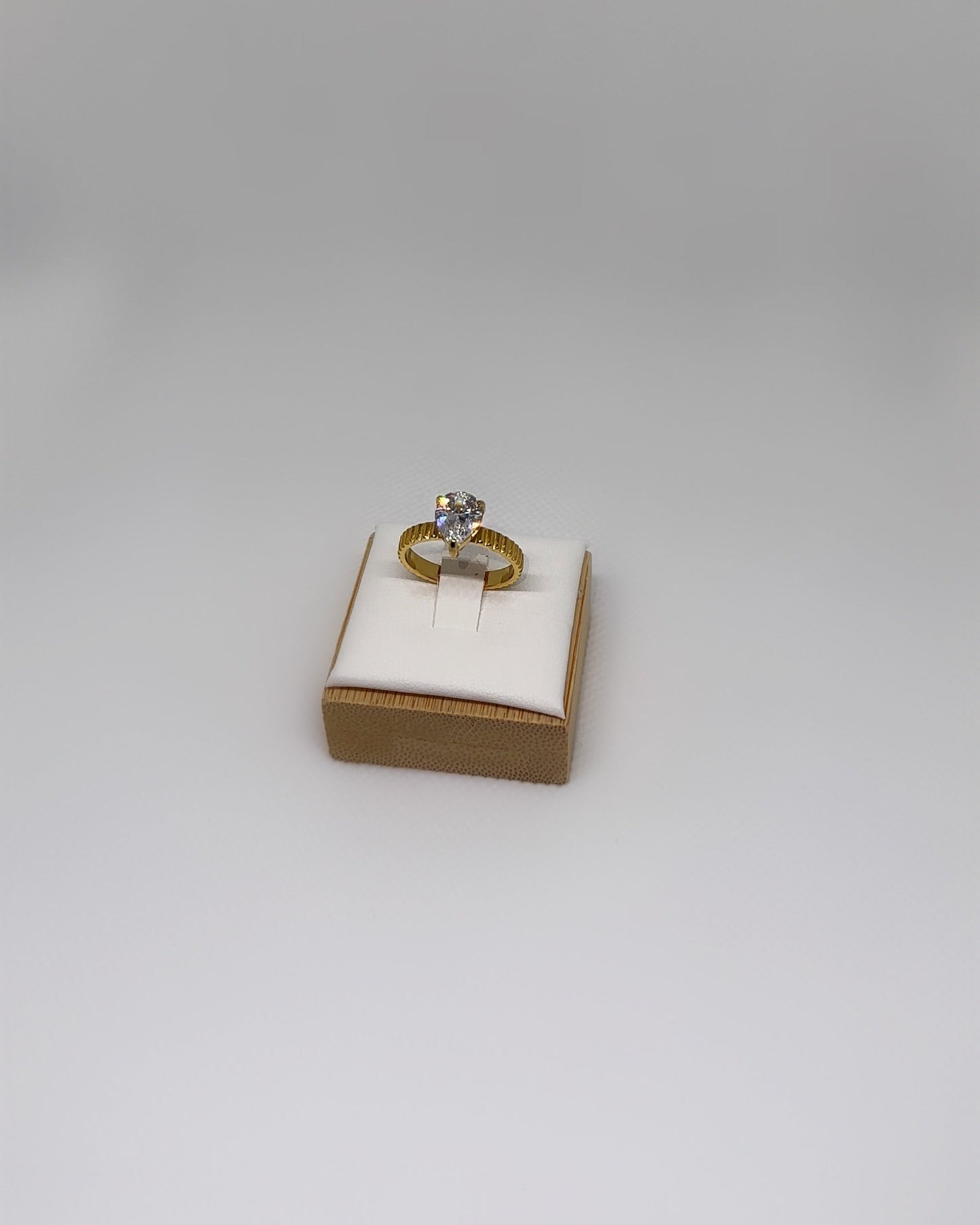 Close-up of the Vow Ring an 18K gold-plated stainless-steel statement ring featuring a pear-cut cubic zirconia, photographed on a soft neutral display.