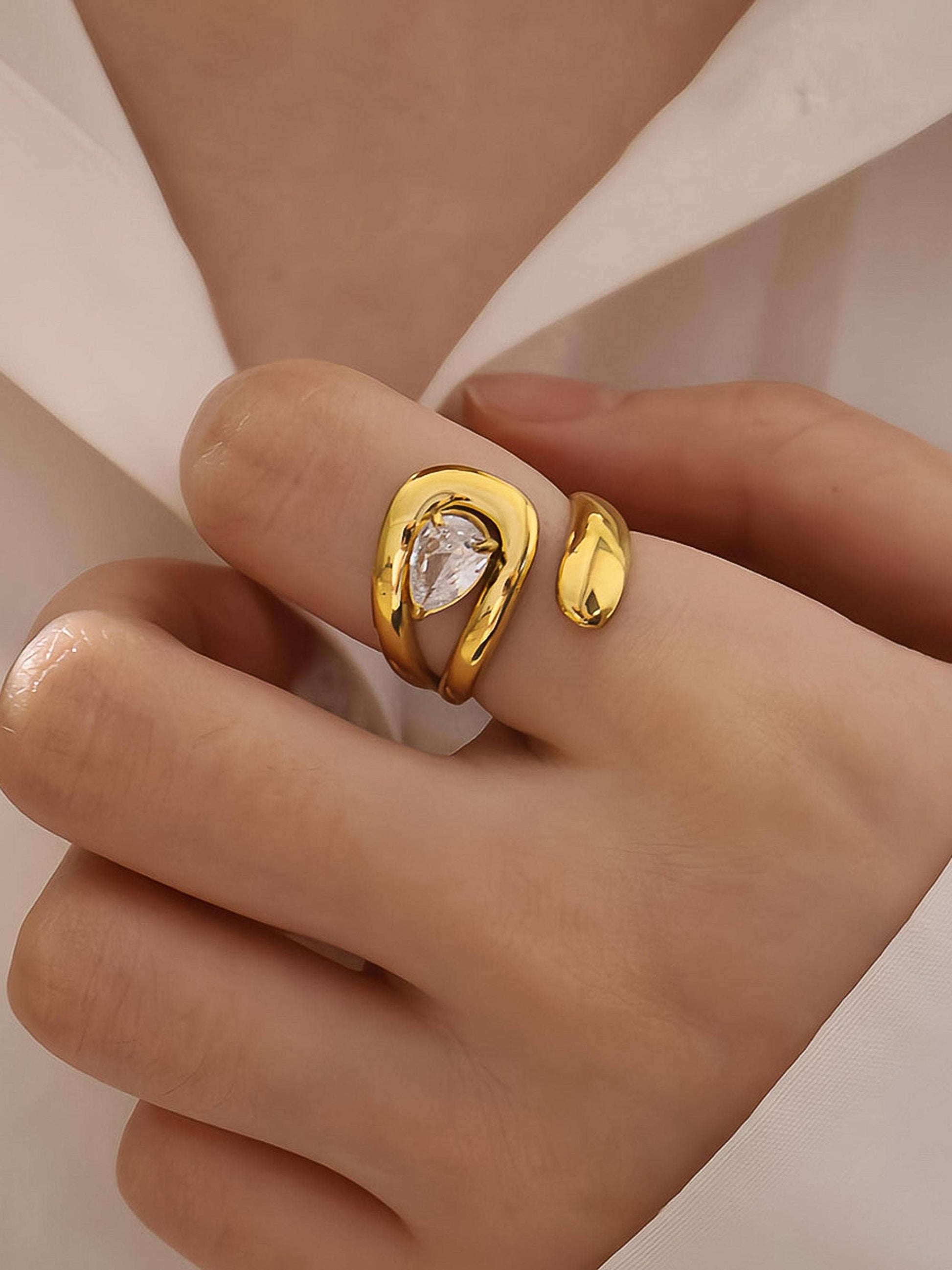 Evoke, an 18K gold-plated stainless steel wrap ring with a CZ crystal by Atelier ÉPURE. Elegant, sculptural, and crafted for everyday sophistication.